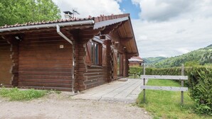 A rustic wooden cabin with a tiled roof, a porch, and a view of the surrounding hills. - Chalet in La Bresse near Forest & Lake (La Bresse)