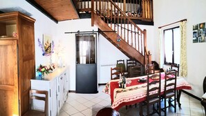Una cocina amplia con zona de comedor, escalera de madera y refrigerador.