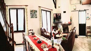 Un comedor con una mesa larga dispuesta para una comida, una chimenea y un televisor al fondo.