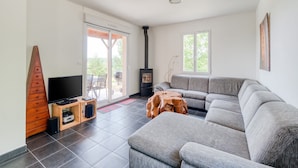 Een moderne woonkamer met een grijze modulaire bank, een flatscreen-tv, een houten kast en een stenen open haard.
