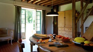 Un comedor con una mesa de madera, sillas, un banco, un reloj y una ventana con cortinas.