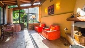 Una habitación acogedora con chimenea, asientos cómodos y una mesa con mantel a rayas.