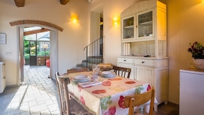 Un comedor con una mesa dispuesta para dos personas, un armario de madera y una escalera que lleva a un nivel superior.
