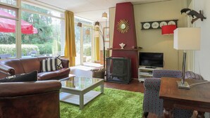 Een gezellige woonkamer met een open haard, een bank, een salontafel en een televisie.