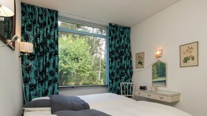 Een slaapkamer met een bed, een dressoir, een stoel en een raam met gordijnen.