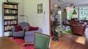 Een gezellige woonkamer met een boekenkast, gestreepten fauteuils, een salontafel en een leren bank.