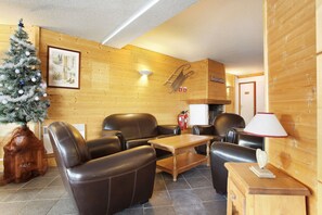 Una habitación acogedora con sillones de cuero, una mesa de madera, un árbol de Navidad y una chimenea.