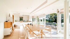 A bright, spacious kitchen with a large dining table and chairs, a view of the outdoors, and modern cabinetry.