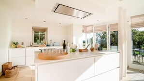 A modern kitchen with a central island, large windows, and a view of the outdoors.