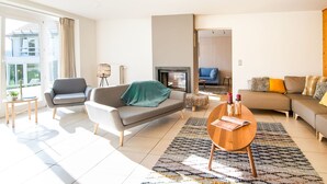 A modern living room with a sofa, armchairs, a coffee table, and a fireplace.