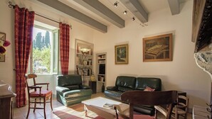 Un saló amb un sofà verd, una cadira de fusta, una taula de centre i una prestatgeria.