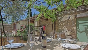 Zona d'esbarjo a l'aire lliure amb taula preparada per a dues persones, amb ampolla de vi, vasos de vi i plats.