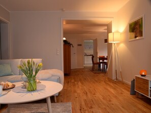 Uma sala de estar moderna com uma mesa redonda, um sofá e uma área de refeições ao fundo.