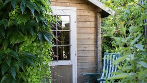 Una baita di legno con una porta, una finestra e una poltrona con cuscino a righe.