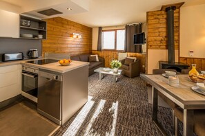 A modern kitchen with an oven, dishwasher, and a dining area with a table and chairs.