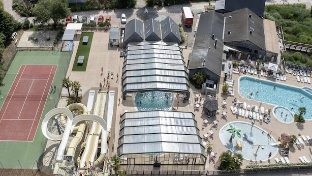 A resort with multiple swimming pools, a tennis court, and a large covered area with a slide.