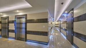 A modern hotel corridor with elevators, a polished floor, and a clean, contemporary design. - Madrid Hotel Gwangju (Gwangju)