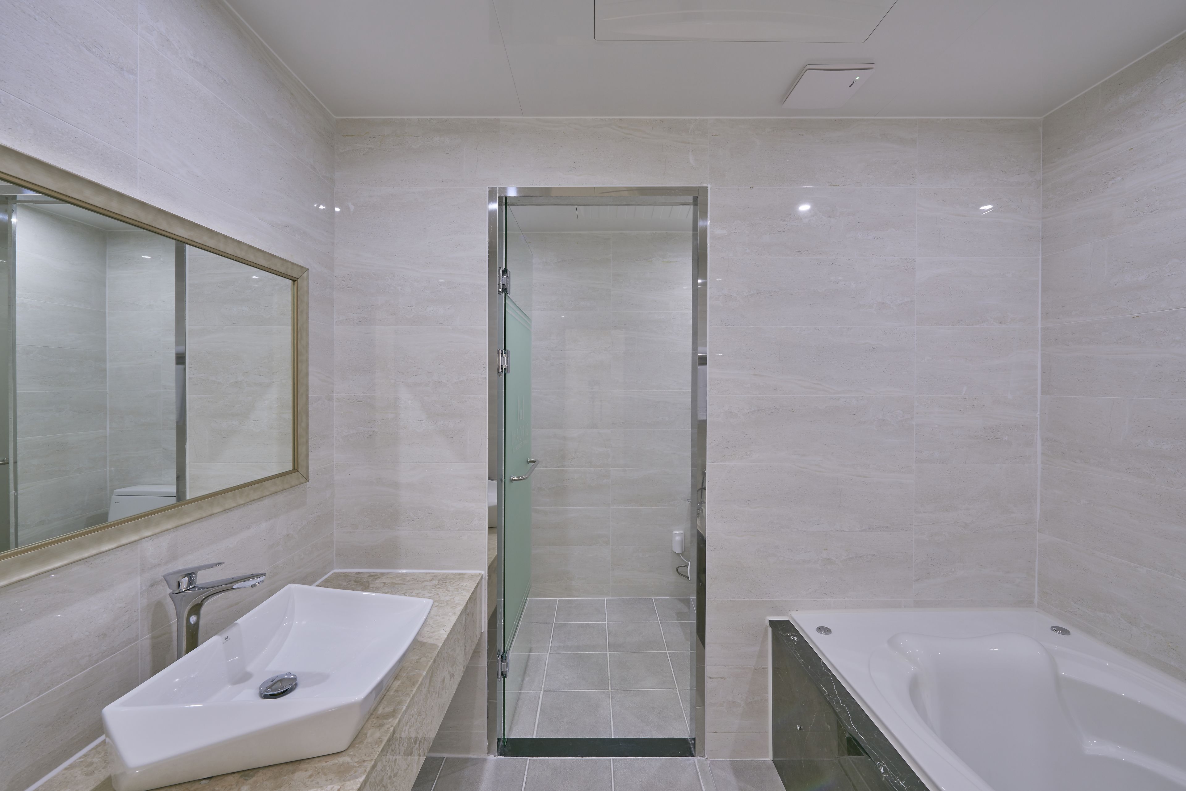 Un baño moderno con cabina de ducha acristalada, lavamanos blanco y bañera.