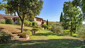 A stone house with a tiled roof, surrounded by a well-maintained garden with a stone staircase leading to the entrance. - Scenic Farmhouse with Pool (Città Della Pieve)