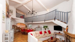 Amplia sala de estar con techo alto, una escalera, chimenea y zona de comedor.