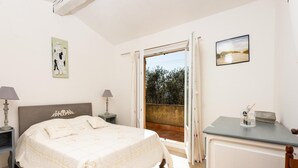 Un dormitorio con cama, dos lámparas de noche, un escritorio con silla, una mesita con un objeto decorativo y un cuadro en la pared.