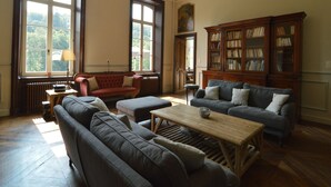 Un ampli saló amb grans finestres, una llar de foc i una biblioteca clàssica.