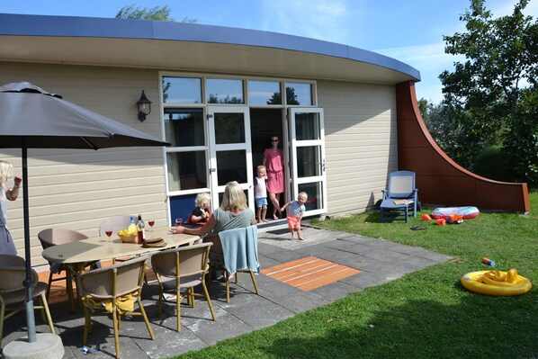 A house with a patio area featuring a table and chairs, a sliding glass door, and a small outdoor seating area with a chair and a table.
