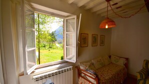 A bedroom with a bed, a window with an open shutter, a radiator, and a hanging lamp. - Dreamy Cottage in Trebbio with Pool (Trebbio)