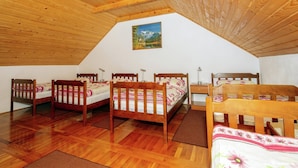 Ein gemütliches Schlafzimmer im Dachgeschoss mit Holzboden, vier hölzernen Betten, einem Bild an der Wand und einer geneigten Decke.