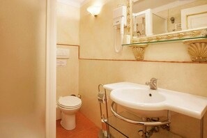 Bathroom features a white toilet, large curved sink, and a mirror above.