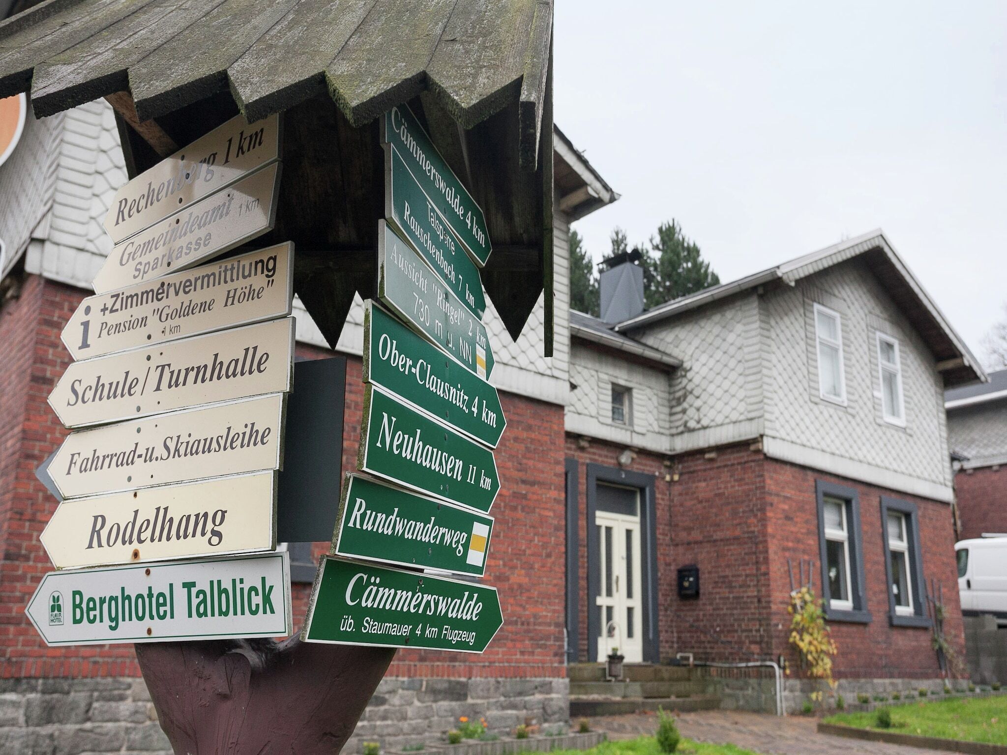 A directional signpost with multiple arrows pointing to various local destinations, including a school, a hotel, and a spa.