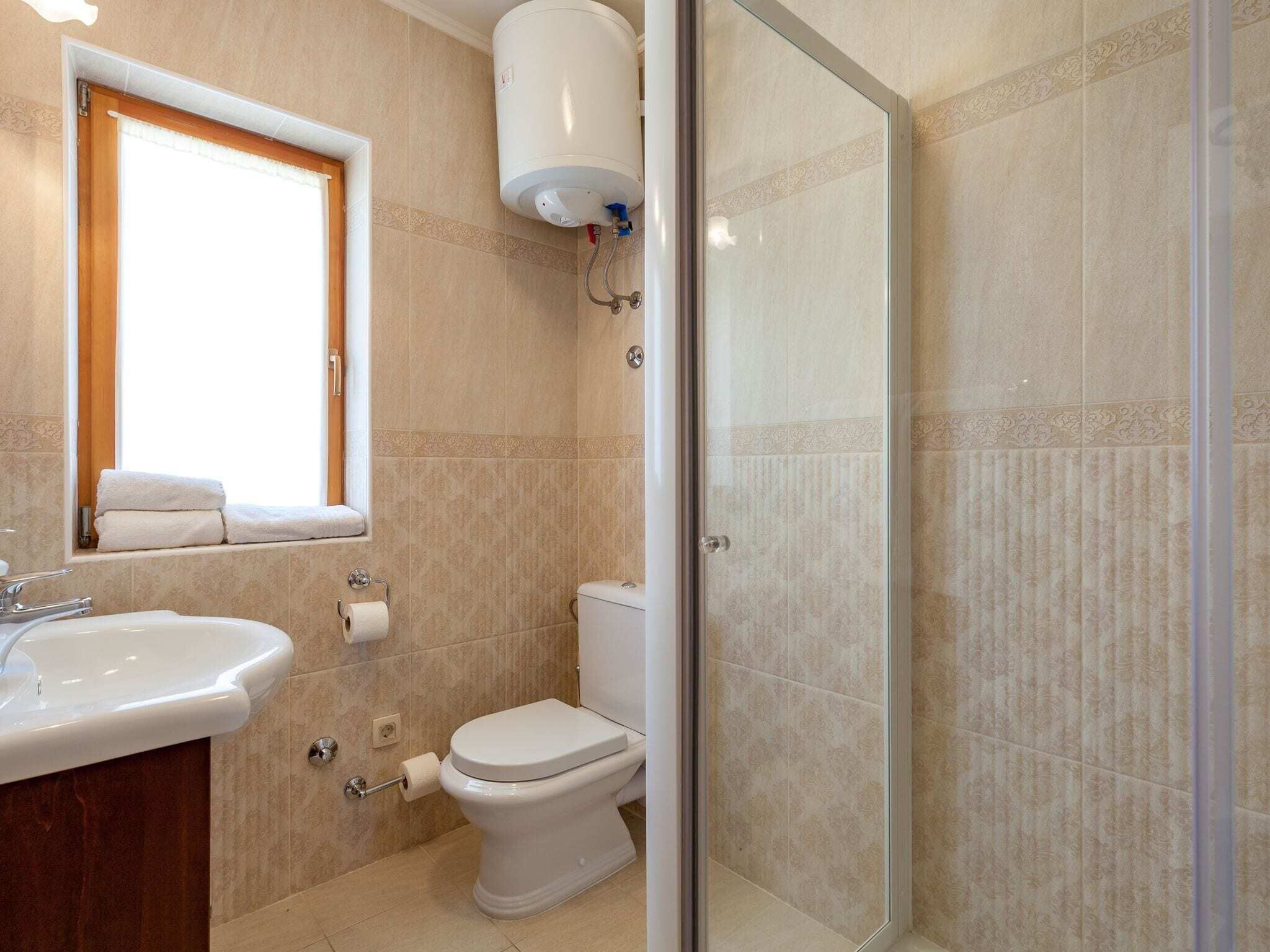 A bathroom with a toilet, sink, and a window.
