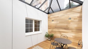 A modern patio with a wooden wall, a window, and a table with chairs.