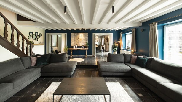 A modern living room with a sectional sofa, a coffee table, and a staircase with wooden railings.