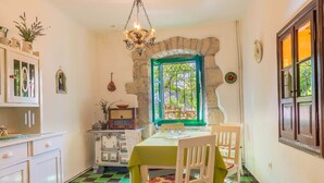 A dining area with a table set for two, a chandelier, and a window with a green frame.