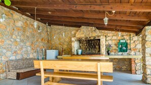 A rustic stone-walled room with a wooden bench, a stone fireplace, and hanging lanterns.