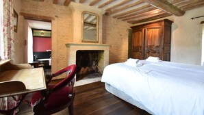A bedroom with a bed, a wooden wardrobe, a fireplace, and a dining area with a table and chairs. - Elegant Manor Retreat Normandy (Lantheuil)