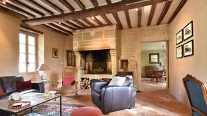 A cozy living room with a fireplace, leather sofas, a coffee table, and a dining area in the background. - Elegant Manor Retreat Normandy (Lantheuil)
