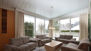 A spacious living room with a large window, a wooden coffee table, and multiple sofas. - Spacious Home with Garden (Waimes)