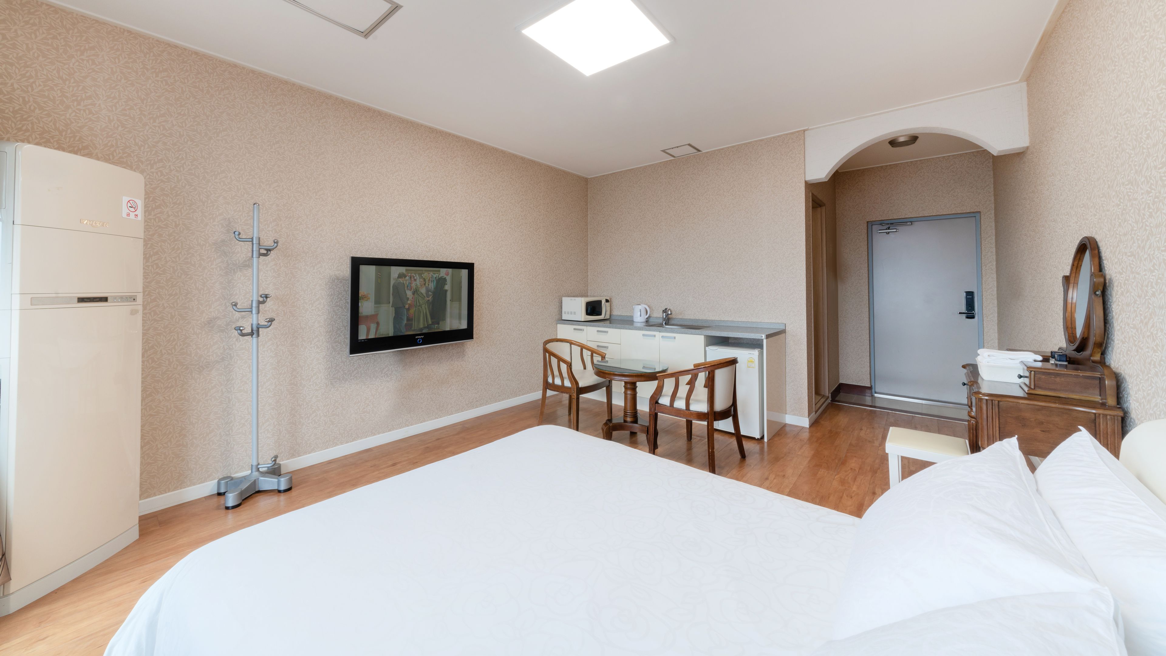A hotel room with a bed, a desk with a chair, a television, a microwave, and a small refrigerator.