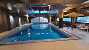 Una piscina techada, abierta desde las 15:00 hasta las 21:00, sombrillas
