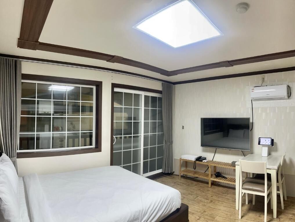 A hotel room with a bed, a desk, a television, and a skylight.