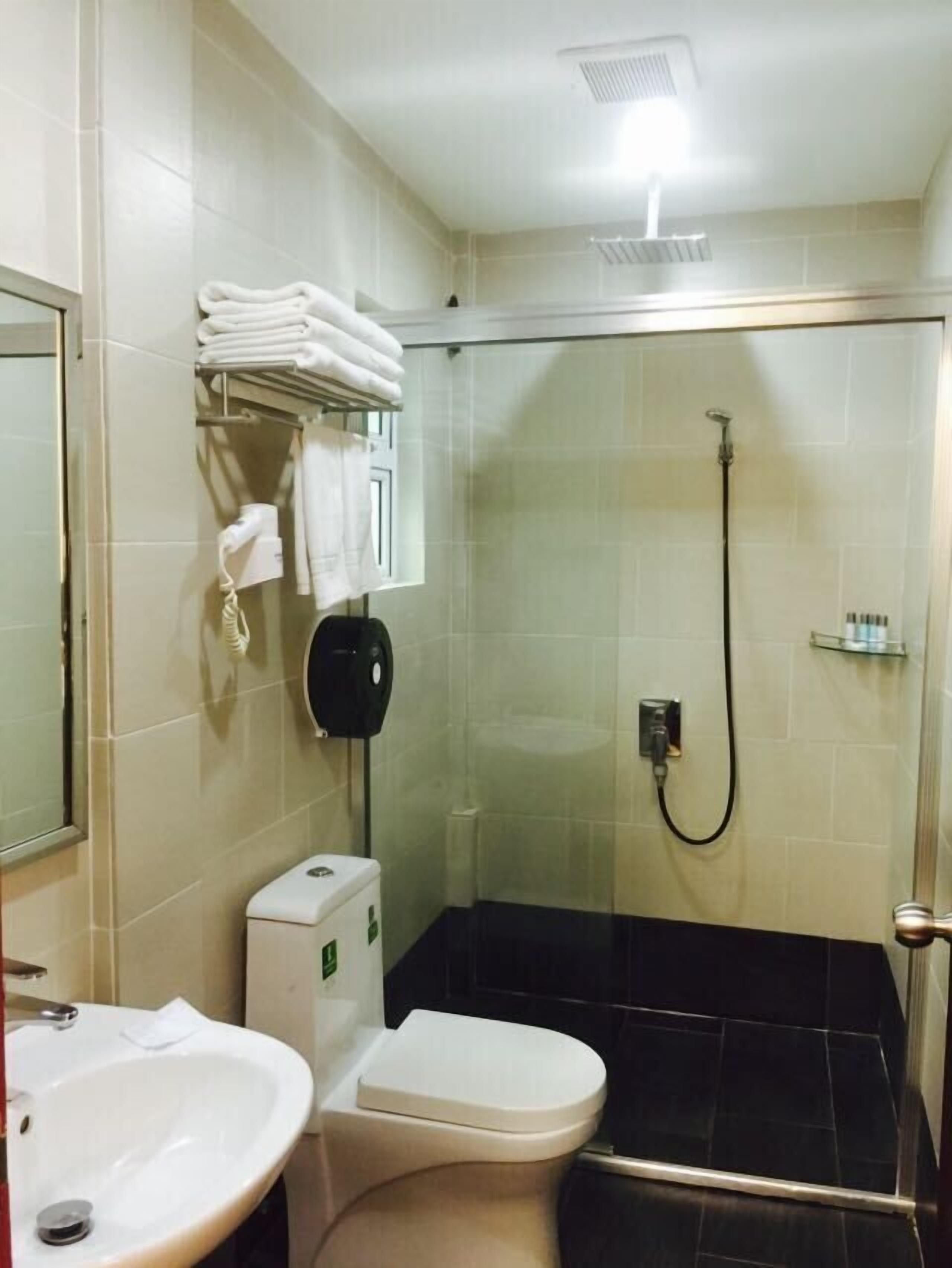 A small bathroom with a toilet, sink, and shower.