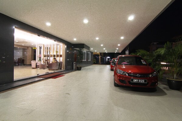A modern building with a glass facade, a red car parked outside, and a well-lit interior. - Kingsley Hotel (Miri)
