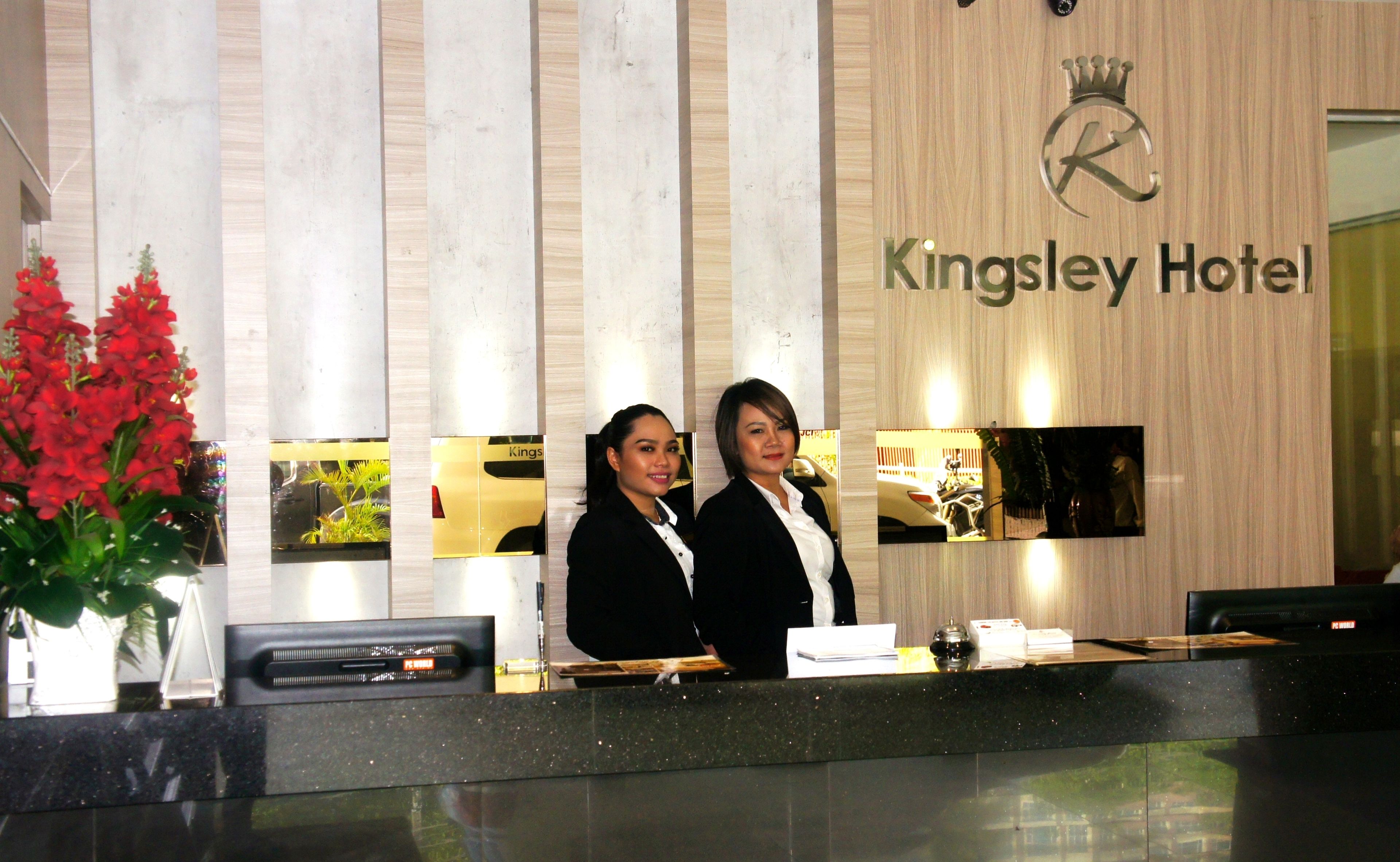 A reception desk at Kingsley Hotel with a modern design, a logo above the name, and a reflection of the hotel interior.
