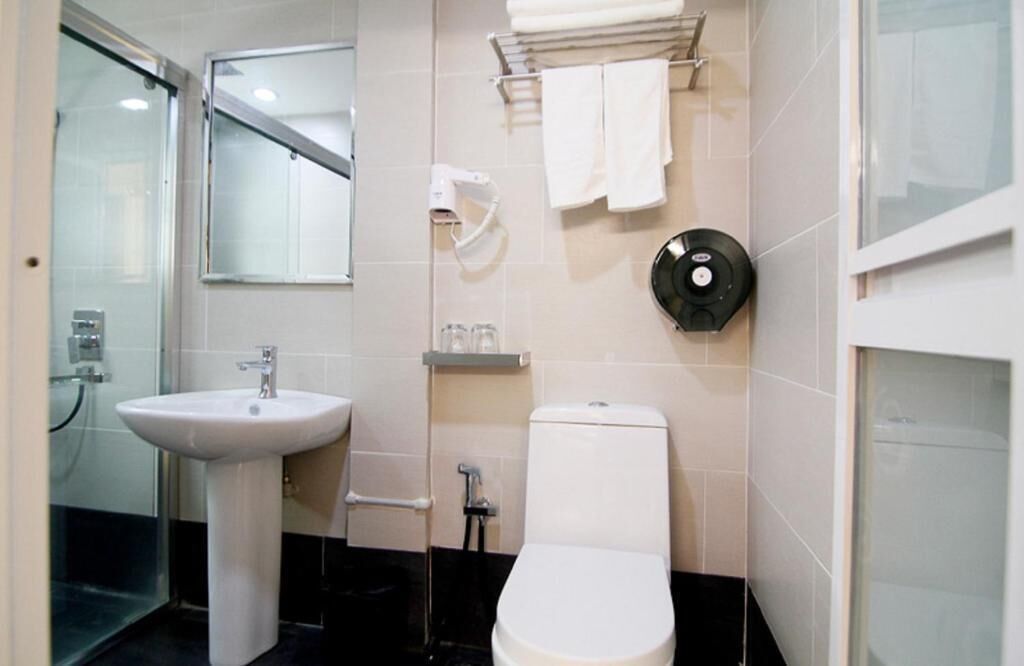 A bathroom with a white sink, toilet, and glass shower enclosure.