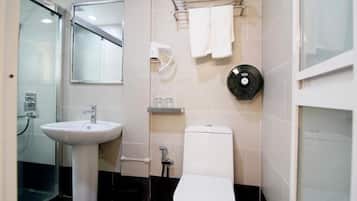 A bathroom with a white sink, toilet, and glass shower enclosure.