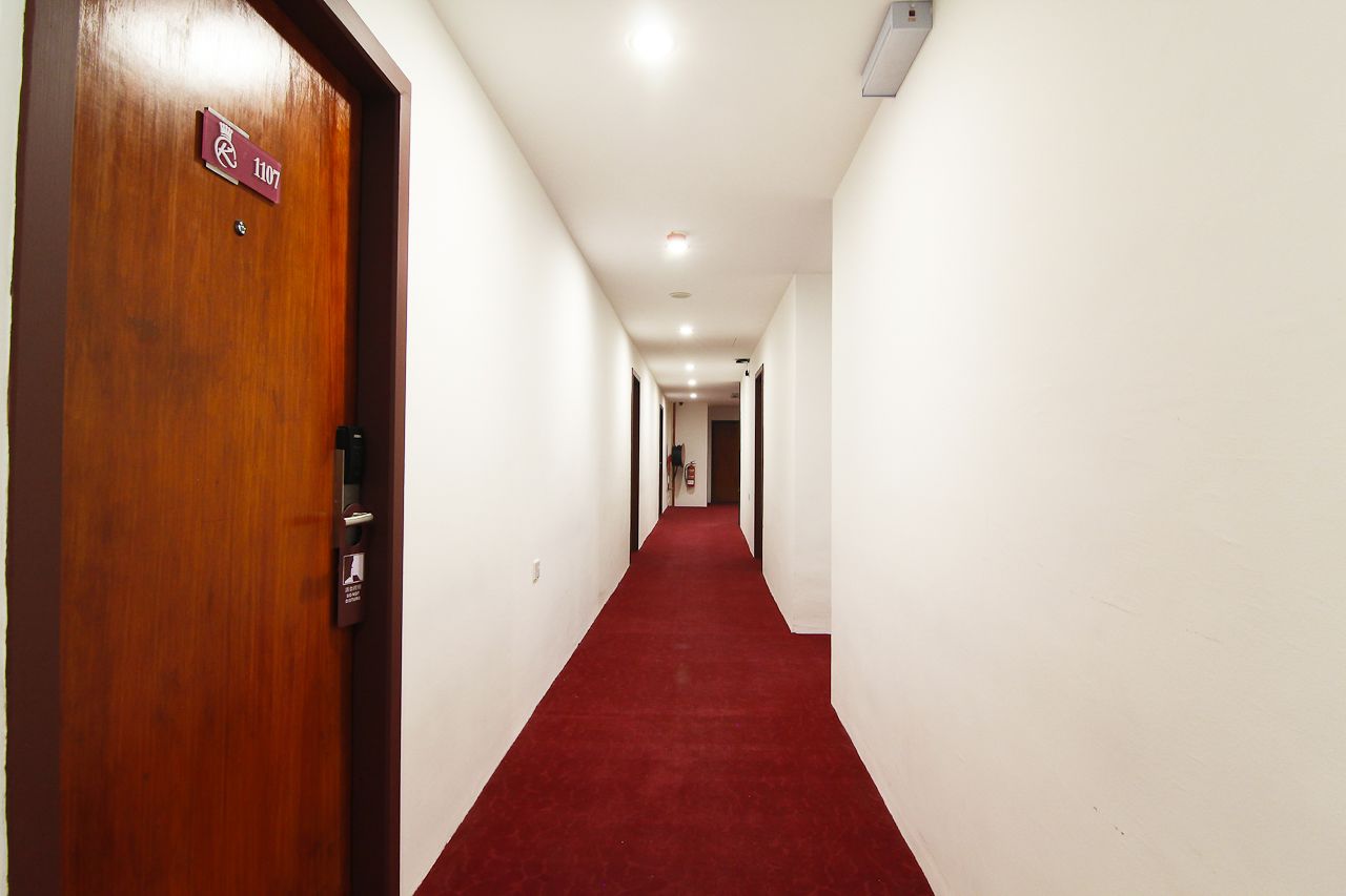 A hallway with a red carpet, white walls, and a wooden door with a sign indicating room number 1107.