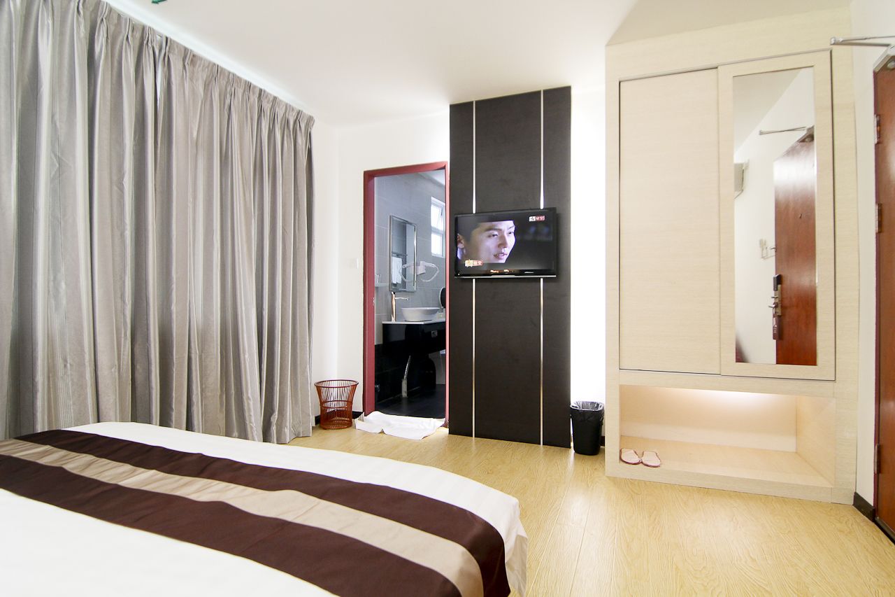 Habitación de hotel con cama, televisor, armario y espejo.
