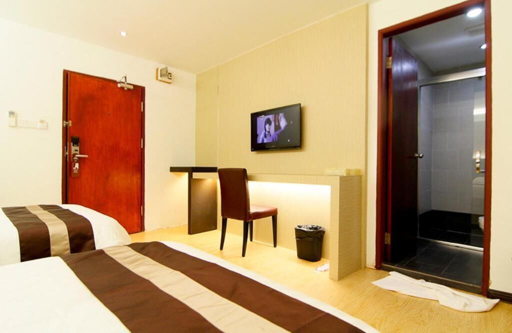Une chambre d’hôtel avec deux lits, un bureau, une chaise, une télévision et un espace douche.